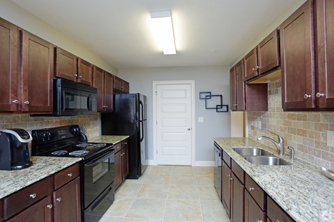 Modern kitchen with black appliances and granite counter tops at Grand Reserve at Pelham in Pelham, AL